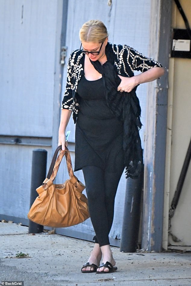 The mother of two looked casual in a black cardigan and leggings, paired with a blouse and scarf and carrying a large brown handbag