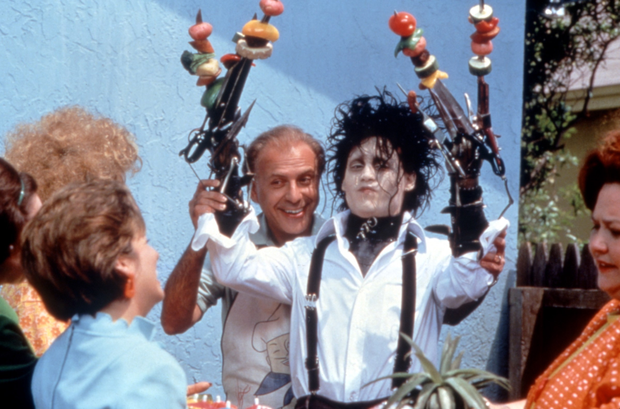 Edward Scissorhands (Johnny Depp) looks extremely uncomfortable as Alan Arkin shows his knife-stained hands covered in shish kebab vegetables during a picnic in Edward Scissorhands