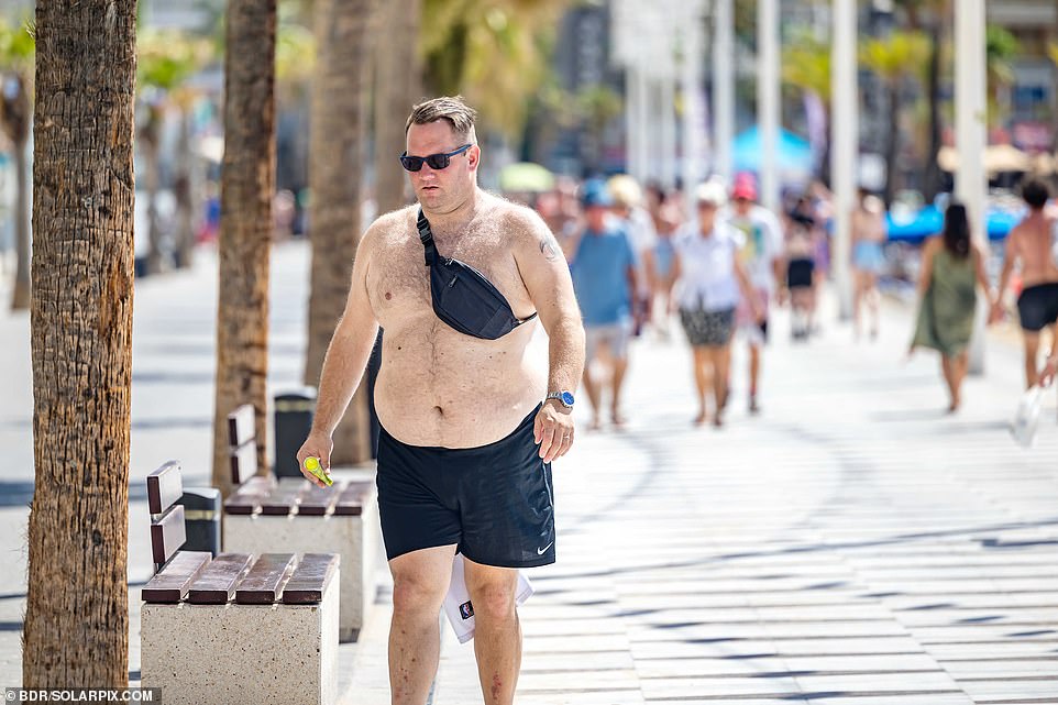 A shirtless Brit enjoys the sun in Benidorm, away from the autumn chill in the UK.