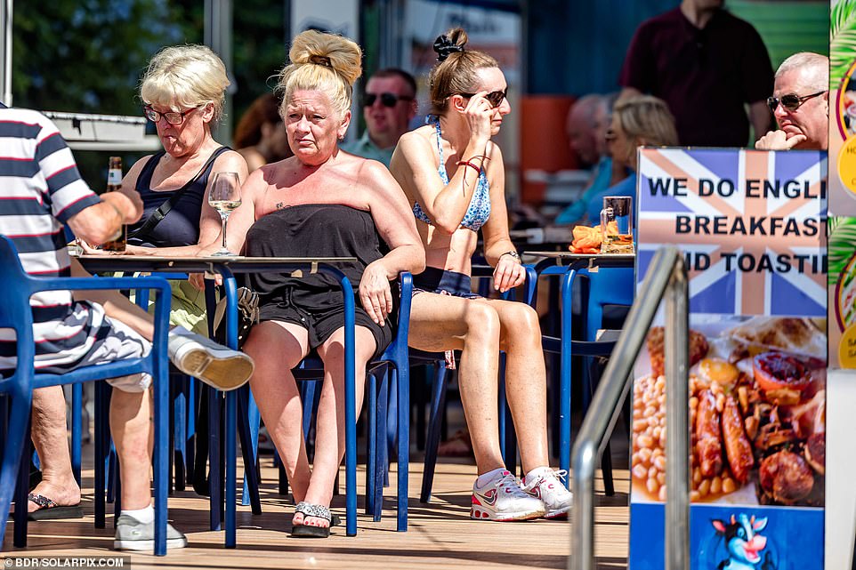 Holidaymakers and expats sit at tables in a restaurant advertising its English breakfast