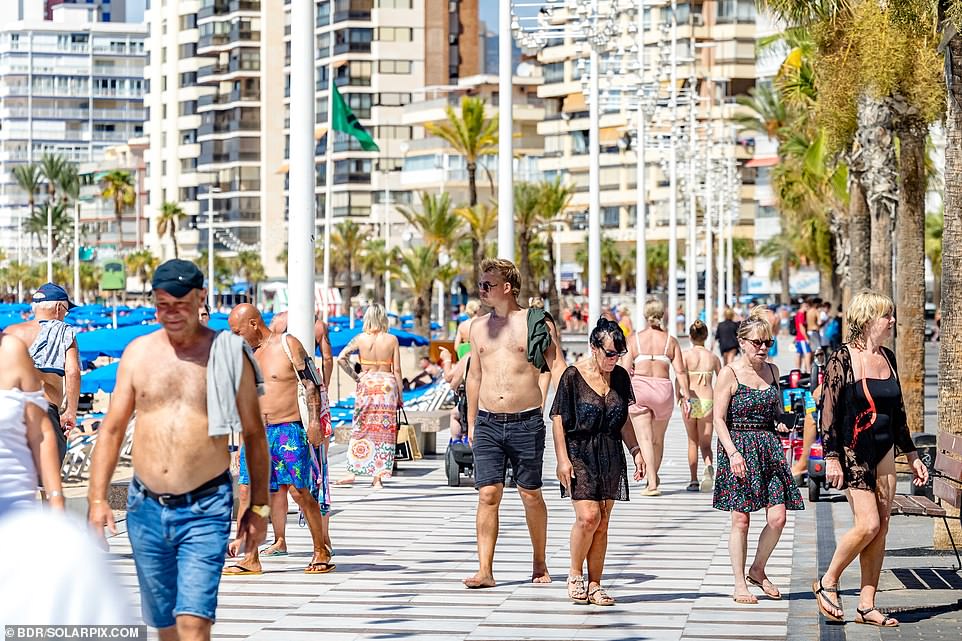 Holidaymakers walk along the beach in Benidorm on Wednesday