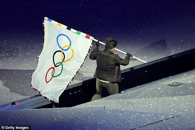 He passed the flag to mountain biker Kate Courtney as we watched him work to add the Olympic rings to the iconic Hollywood sign