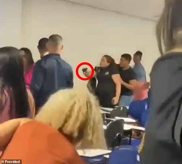 An Alagoas Civil Police officer, who attends Estácio College, points her service weapon at a student during a brawl after she told her to lower her voice during a lecture