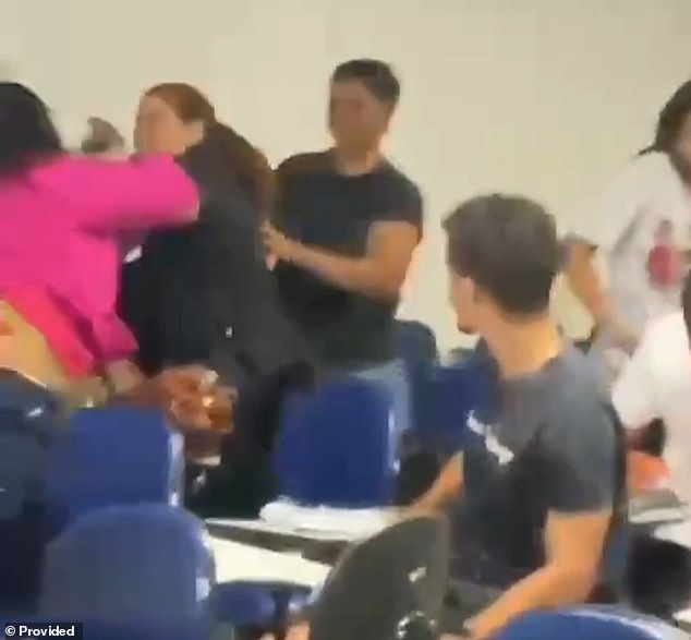 A female student tries to separate two fighting students before one of them, who is also a police officer, points her unloaded gun at her classmate at Estácio College in Maceió, Brazil, last Friday. The Alagoas Civil Police are investigating the officer's conduct