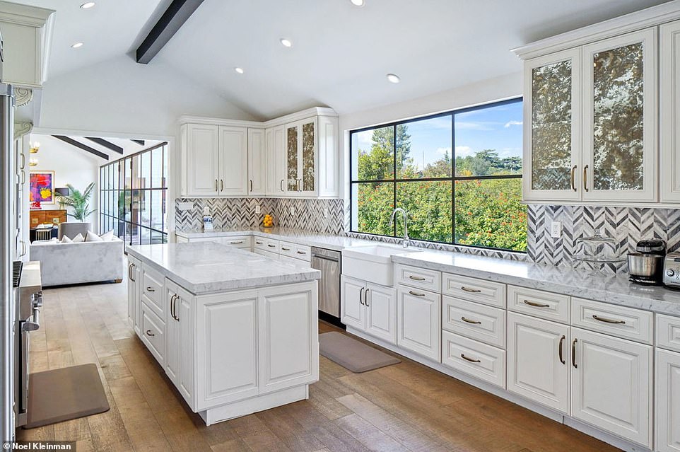 Emmet's kitchen has bright white cabinets and gray-white herringbone backsplash tiles