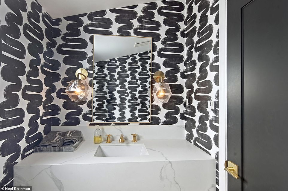 A smaller bathroom features bolder black-and-white wallpaper and gold detailing, along with an angular granite sink