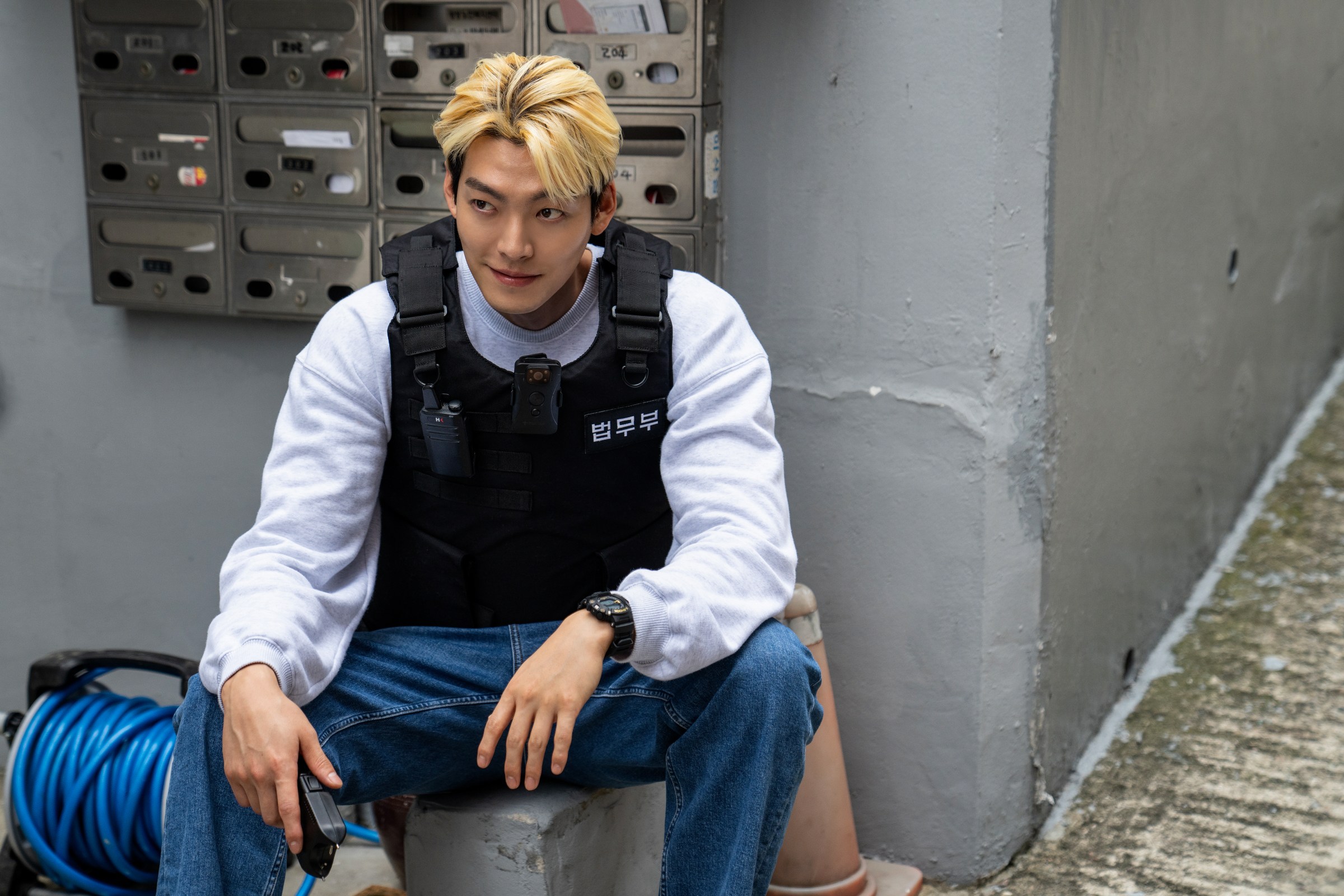 A blond man in a bulletproof vest, smiling and with the rank of officer black belt.