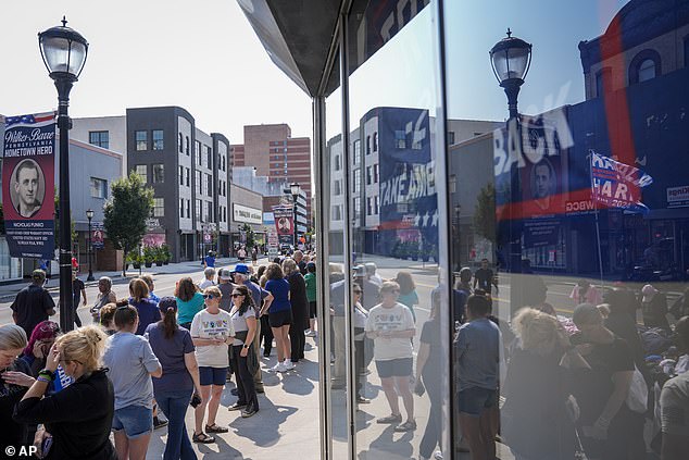 The reflection of a Trump sign is seen in the window of a store selling reptiles in downtown Wilkes-Barre, Pennsylvania, as supporters of Vice President Kamala Harris line up to see the Democratic nominee