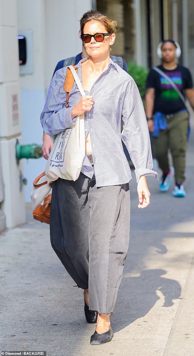 She wore an unbuttoned purple and white striped shirt, a pair of very wide, charcoal trousers with a frayed hem and worn black leather ballerina flats