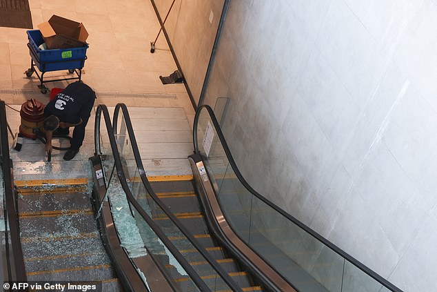 A worker sweeps broken glass from an escalator damaged by a missile fired from Yemen at a train station in the Israeli city of Modin