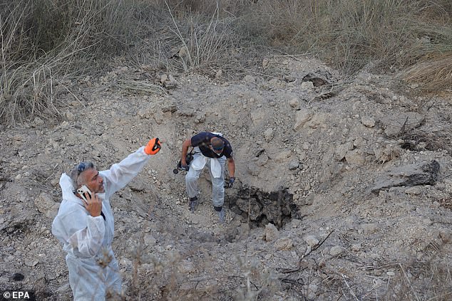 The Israel Police Bomb Disposal Unit investigates the site of a rocket attack near Kfar Daniel, central Israel