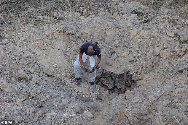 The Israel Police Bomb Disposal Unit investigates the scene of a ground-to-ground rocket impact near Kfar Daniel