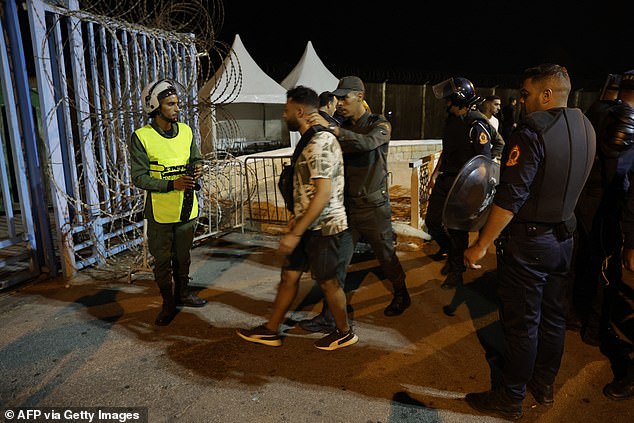 Members of the Moroccan auxiliary forces arrest a man after being deployed to prevent illegal crossings of the land border with the Spanish enclave of Ceuta in Africa