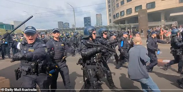 A New South Wales police officer approaches Flower with a baton during a charge. Flower was positioned with news cameramen and was wearing a media credential