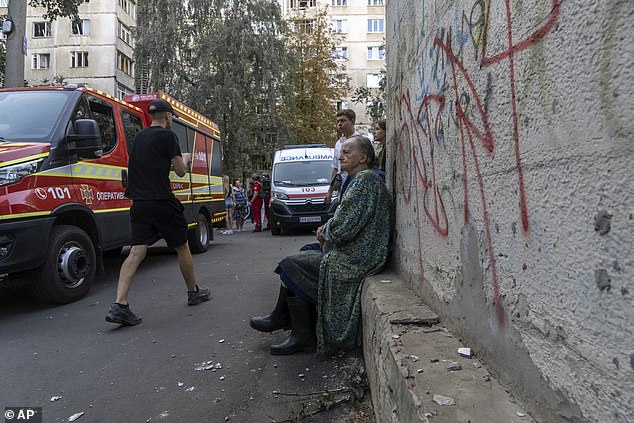 A person sits at the scene after a Russian aircraft bomb hit a multi-storey residential building in Kharkiv