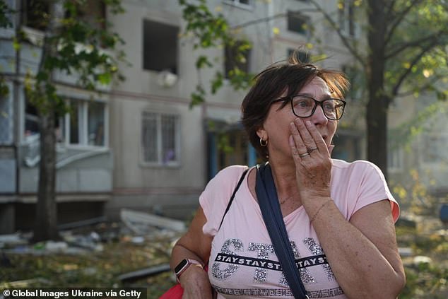 A woman stands in front of a residential building damaged by Russian guided-aircraft fire on September 15, 2024 in Kharkiv.