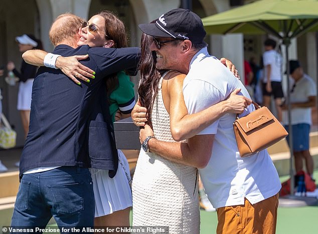 Harry hugs Kelly McKee Zajfen and Meghan hugs Julian during the tennis tournament on Saturday