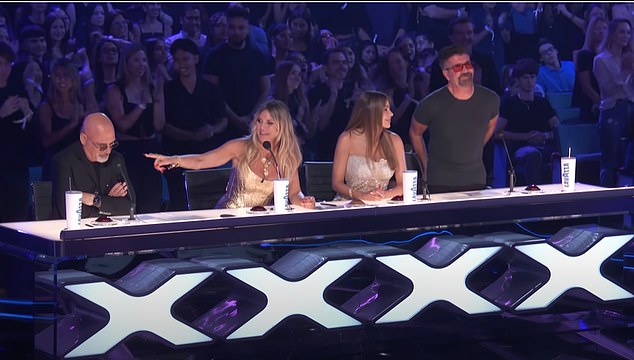 Simon Cowell (right) joined in the standing ovation for the group's performance, but Mandel (left) remained unmoved as the audience booed his sharp remarks