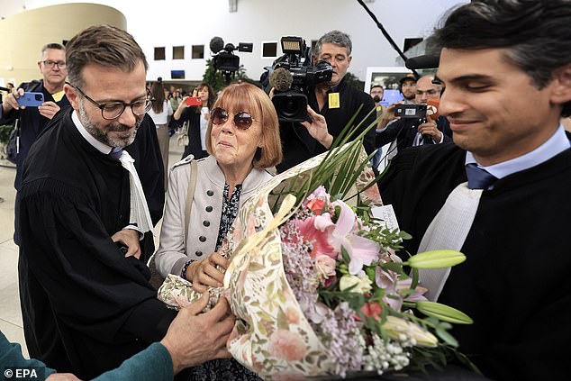 Gisele Pelicot (center), flanked by her lawyers, receives flowers from a member of the public during the trial of her ex-husband for rape, at the criminal court in Avignon on September 17