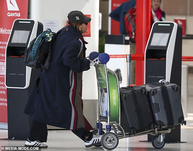 The pretty lady added a touch of glamour to her look with silver hoop earrings and appeared to be in good spirits as she loaded her luggage onto a trolley and headed out