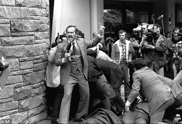 An unidentified Secret Service agent, automatic weapon drawn, shouts orders after shots are fired at President Ronald Reagan outside a Washington hotel on Monday, March 30, 1981.