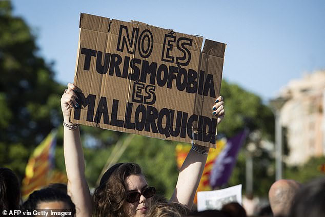 A protester holds a sign reading 'It's not tourismophobia, it's Mallorcicide' during a protest