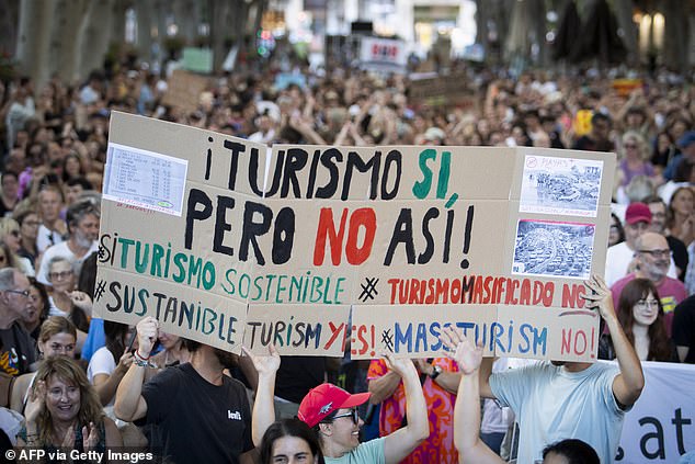 Protesters hold up a sign reading 'tourism yes, but not like that' during a march in Palma