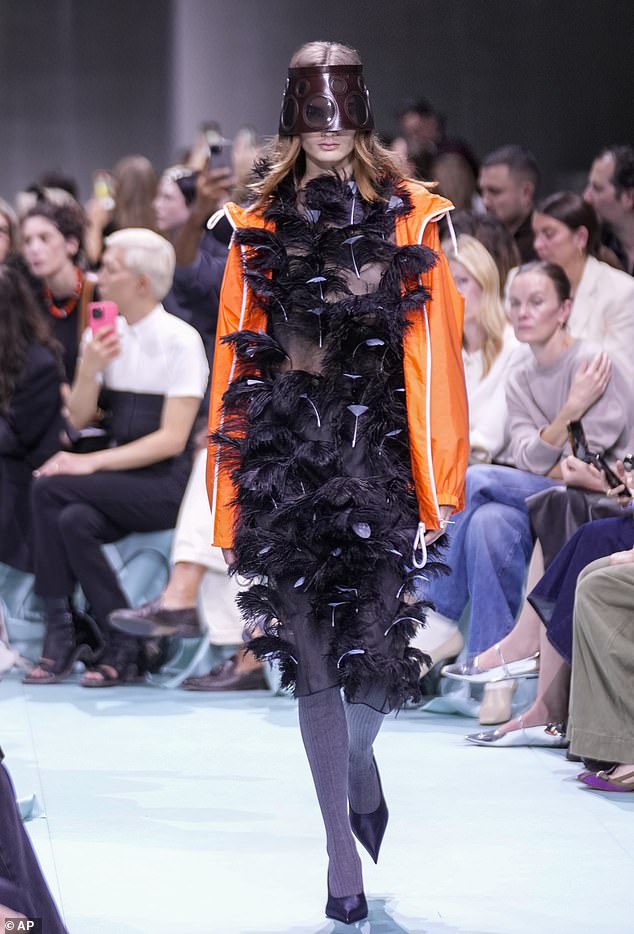 A dark feathered dress was worn with an orange raincoat in the striking presentation