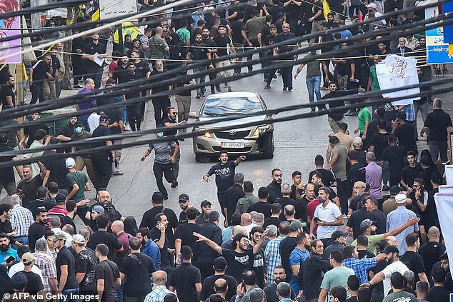 People react around a car after an explosion was reported during the funeral of those killed when hundreds of pagers exploded the day before in the southern suburbs of Beirut, Lebanon on September 18, 2024