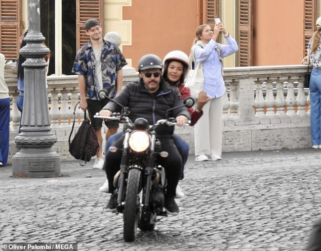 He wore a black puffer jacket as he rode around the famous Acqua Paola fountain on a motorbike with Italian actress Nicole Grimaudo, 44, in the backseat