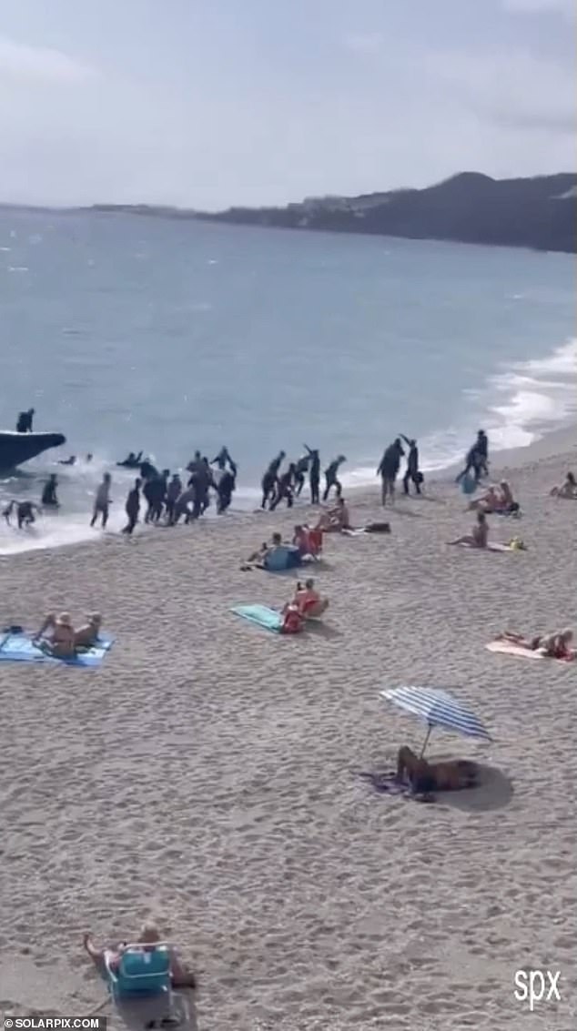 Shocked tourists sat bolt upright in their deck chairs as the small vessel approached the shoreline and the men disembarked before running or walking past them