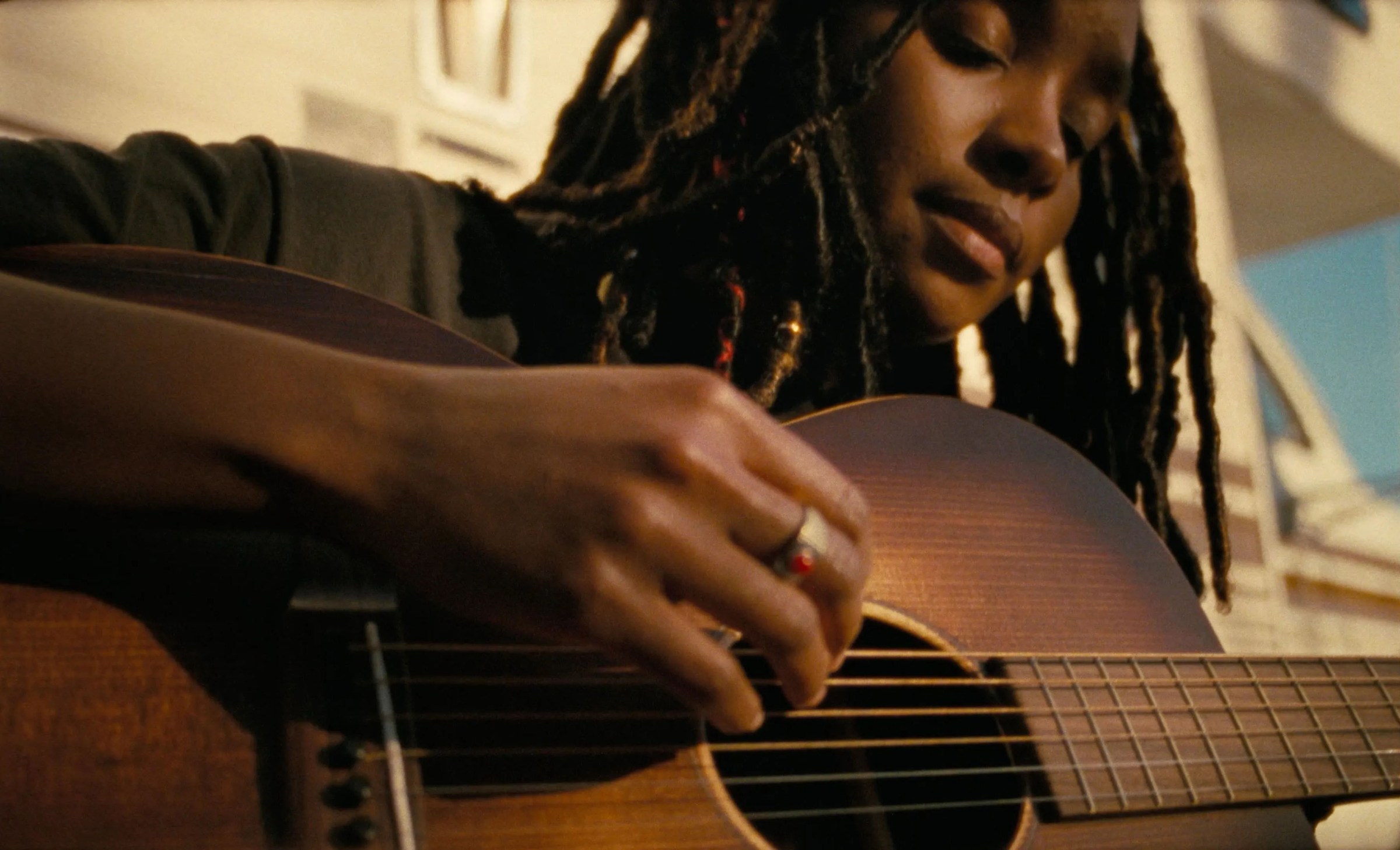 A close-up of a woman playing guitar in Dandelion.