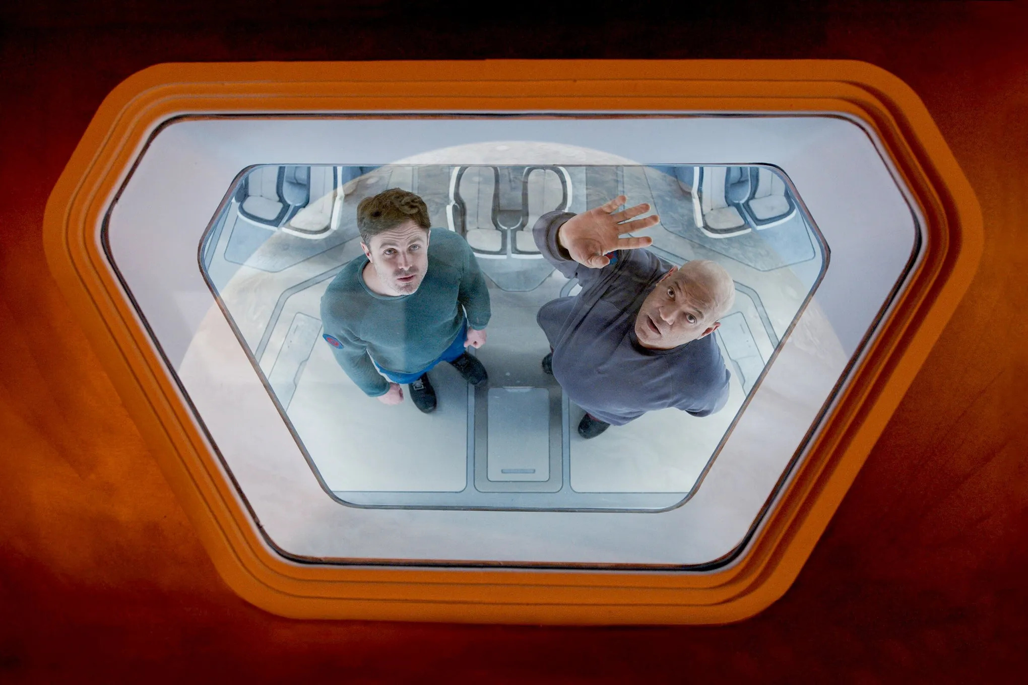 Casey Affleck and Laurence Fishburne stare through the porthole of a spaceship at a nearby planet in Slingshot.