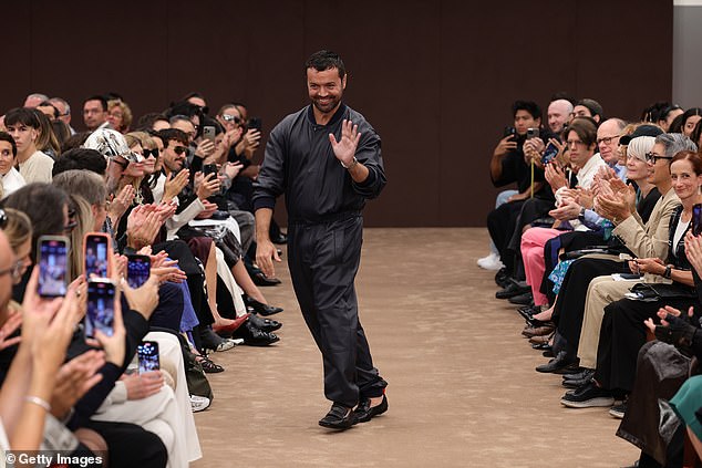 Fashion designer Rocco Iannone smiles and waves as he is cheered after the show