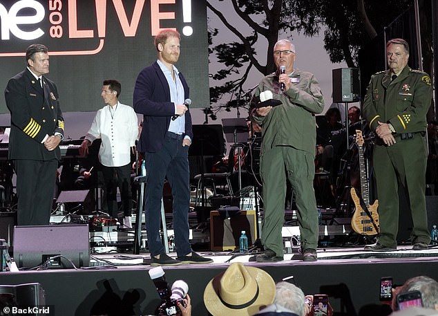 Prince Harry is pictured presenting an award to local helicopter pilot Loren Courtney on stage early in the evening