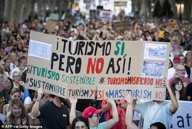 Protesters hold up a sign reading 'tourism yes, but not like that' during the march in Palma