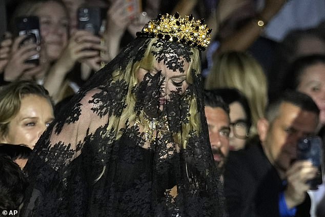 Madonna showed off her bold sense of style in a black lace veil and a gold crown as she took her place in line