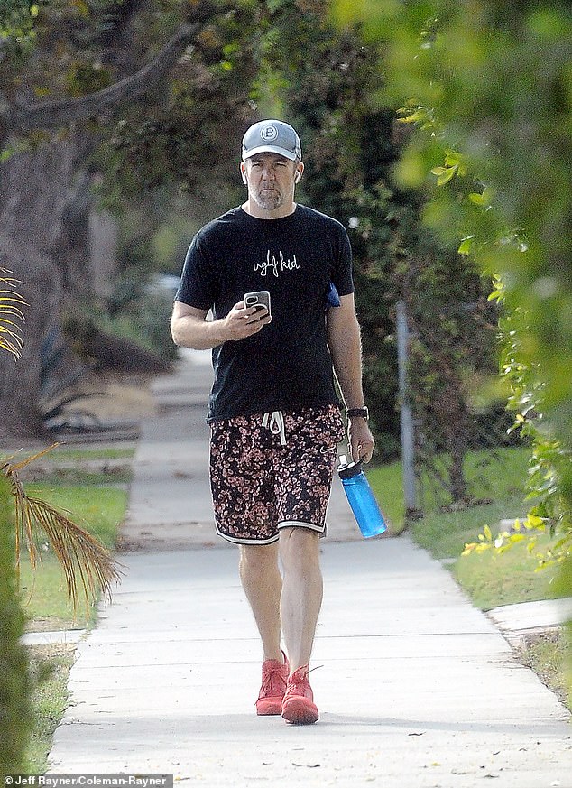 The actor also looked casual in a pair of eye-catching pink and black board shorts and a black T-shirt with the words Ugly Kid printed on the front.