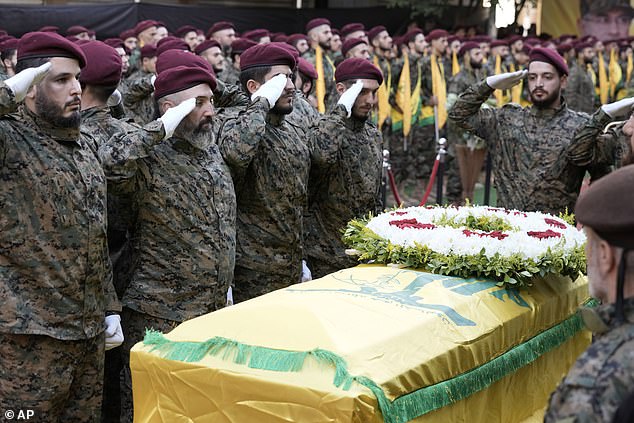 Hezbollah members salute the coffin of Hezbollah commander Ibrahim Akil during the funeral procession in Beirut's southern suburb