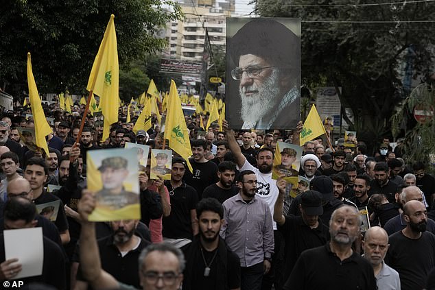 Supporters held up Hezbollah flags and photos of Akil (left) and Supreme Leader Ayatollah Ali Khamenei (right) during Akil's funeral procession