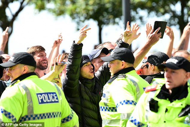 Police officers stand by as far-right protesters shout 'Enough is enough' in response to fatal stabbings in Southport