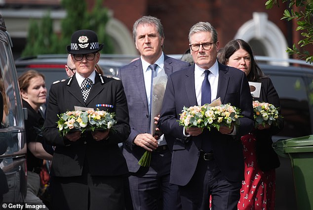 Prime Minister Sir Keir Starmer walks with floral tributes for the three child victims of a knife attack in Southport