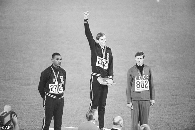 Gold medalist Dick Fosbury raises his arm on the podium of honor at the Olympic Stadium in 1968