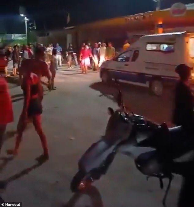 Residents surround an ambulance at the police station which was stormed by an angry mob on Thursday and dragged out Gregorio da Silva, who reportedly confessed to the rape and murder of one-year-old Laylla de Assis, and set his body on fire