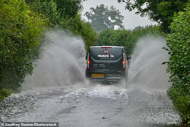 A vehicle drives through flood water in Dunsden, Oxfordshire this morning after heavy rainfall