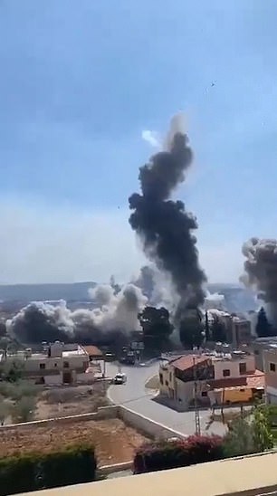 A person films from a rooftop in Lebanon as airstrikes approach where he is standing