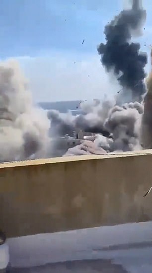 A person films from a rooftop in Lebanon as airstrikes approach where he is standing