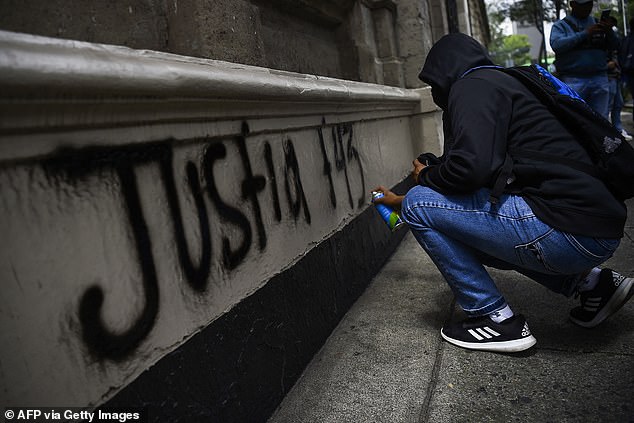 A student paints graffiti on the entrance to the Ministry of the Interior during a demonstration demanding justice for the 43 students of the Rural Normal School in Ayotzinapa who disappeared on September 26, 2014.