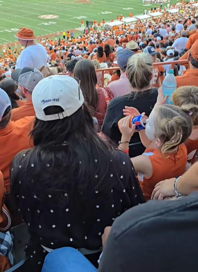 The child's mother appears to be sitting to the left of the toddler and does not stop drinking