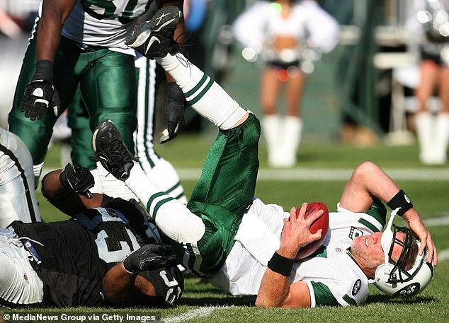 Favre, pictured playing for the New York Jets, clutches his head after falling to the field in 2008